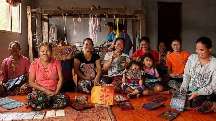 Siphone Vorasan (second from left) invested in looms and now employs several women under the Nam Ngum River Basin Development Project. Photo: Xaykhame Manilasith/ADB. https://greatermekong.org/improving-lives-and-saving-forests-lao-pdr